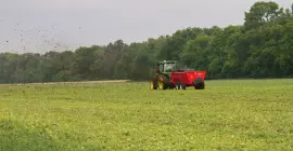 SL 124 bem distante espalhando esterco em um campo.