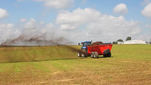 SL 124 distribuindo esterco em um campo.
