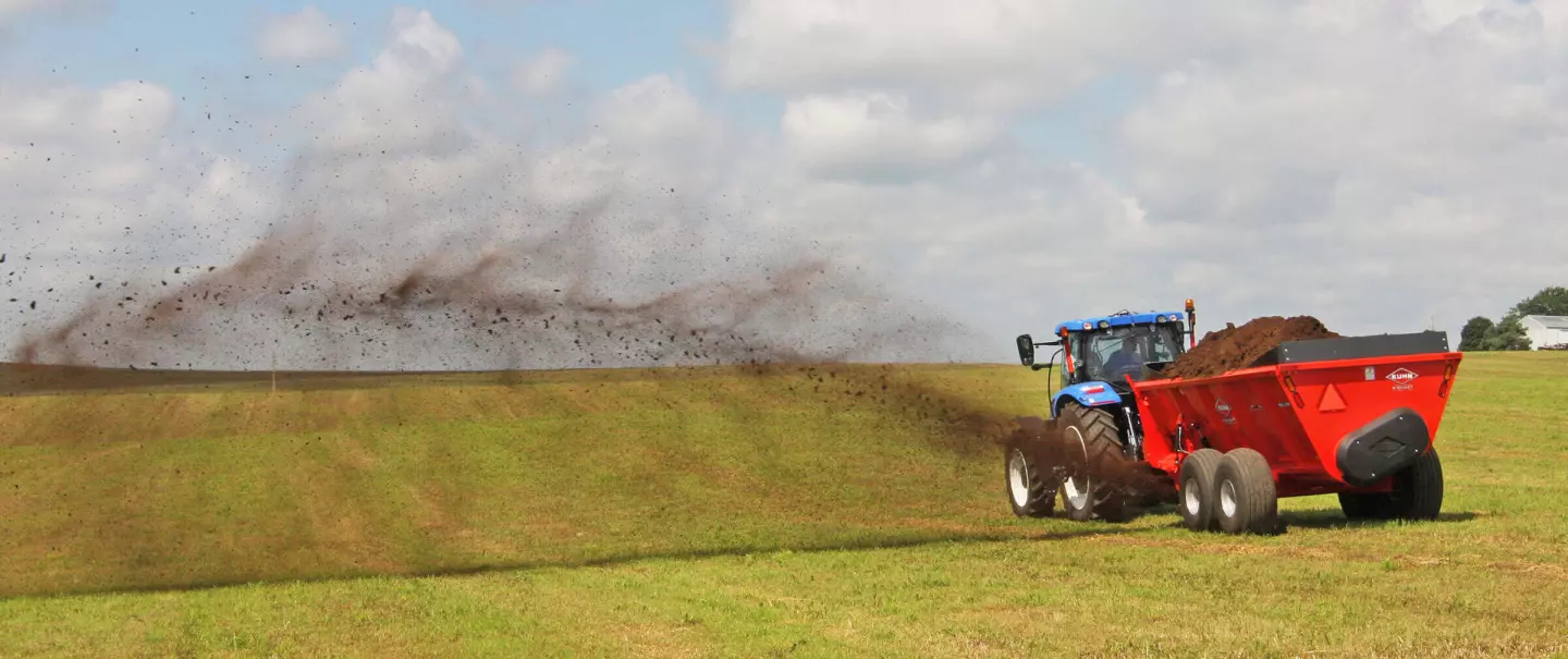 Visão traseira de um SL 124 distribuindo esterco em um campo de feno.