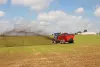 SL 124 bem distante espalhando esterco em um campo.